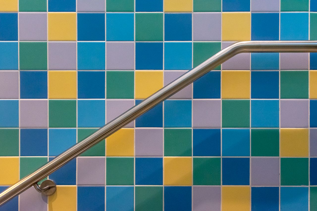 The Art of Drawing Readers In: Your attractive post title goes here Vibrant square tiles in blue, yellow, and green with a sleek stainless steel railing.